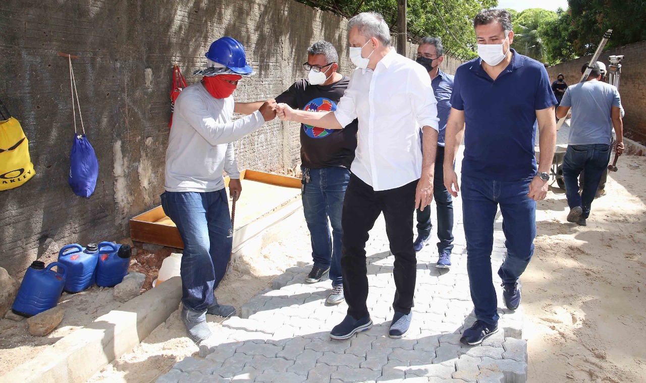 sarto cumprimenta, com os punhos fechados, um operário na obra que ele visitou